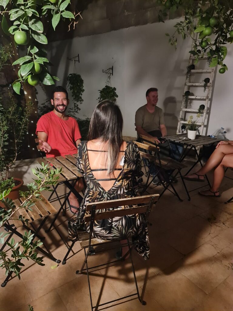 Grupo de personas disfrutando y socializando en la terraza del Hostel On bajo un cielo azul, reflejando un ambiente amistoso y abierto