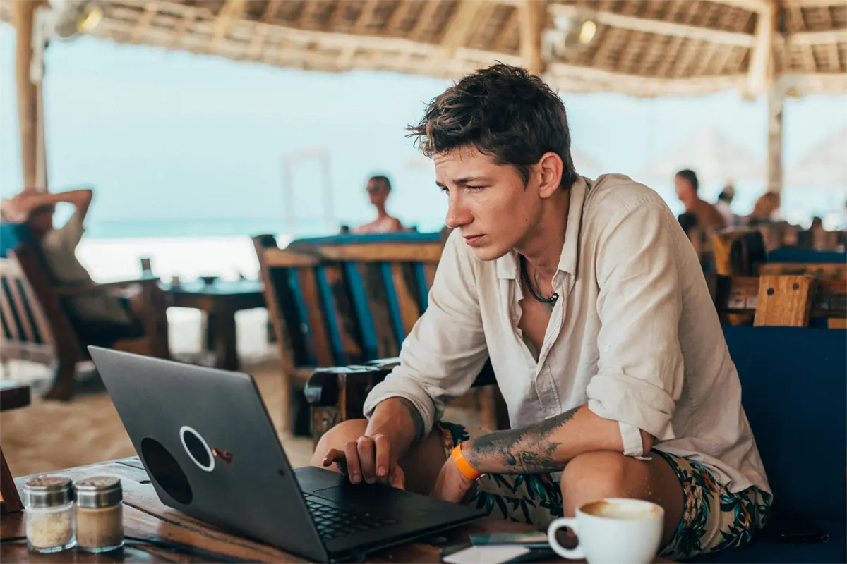 Chico en la playa con ordenador