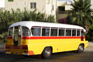 Autobús clásico amarillo y rojo en Malta, símbolo del transporte público maltés y alternativa a llevar tu coche a Malta.