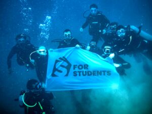 Grupo de estudiantes de Malta for Students buceando en las aguas cristalinas de Malta con bandera bajo el mar