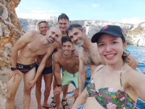 Grupo de estudiantes sonrientes tras una inmersión de buceo en Malta, rodeados de acantilados y aguas turquesas, durante su curso con Malta for Students