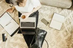 Persona adulta estudiando inglés desde casa con portátil, cuaderno y café en un ambiente tranquilo